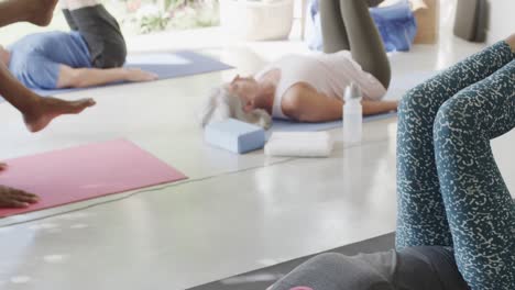 diversos ancianos centrados haciendo pilates, tendidos en esteras con una entrenadora, sin alteración, en cámara lenta.