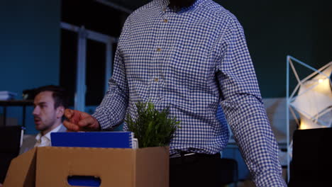 young bearded businessman packing his stuff in the office late at night