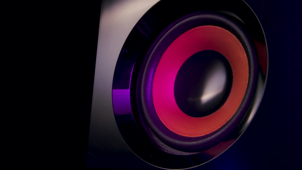 Macro close up of black vibrating membranes loud sound speaker in colorful neon lighting. Close up. Slow motion