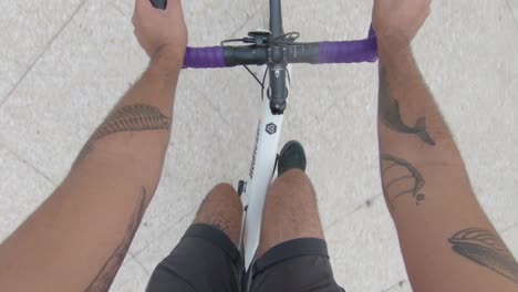 pov tattooed young man in shorts enjoying a ride on a fixie at the street
