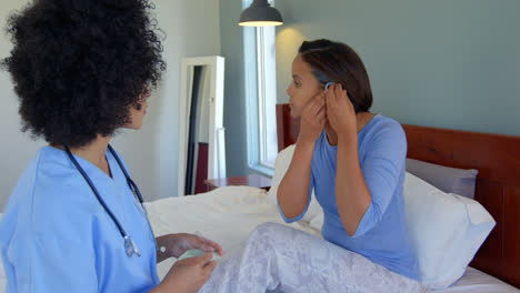 mixed race woman inserting hearing aid in her ear at home 4k