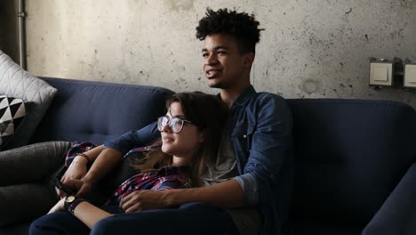 cute happy couple of young hipsters lying on the couch, making silly faces,trying to find a perfect tv channel. leisure time, enjoying youth, living together. relationship goals.