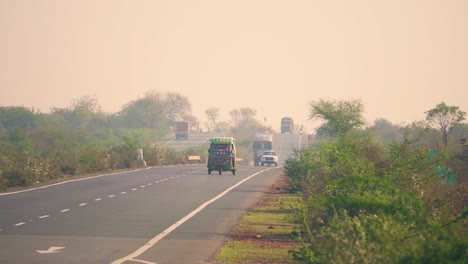 a tempo rikshaw and cars moving on a national hjghway motor road in central india