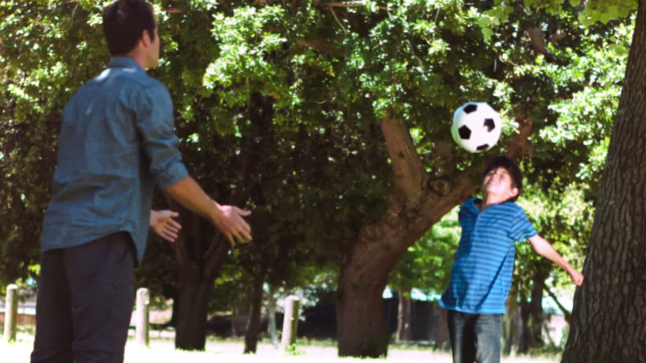 niño jugando al fútbol en cámara lenta con un adulto