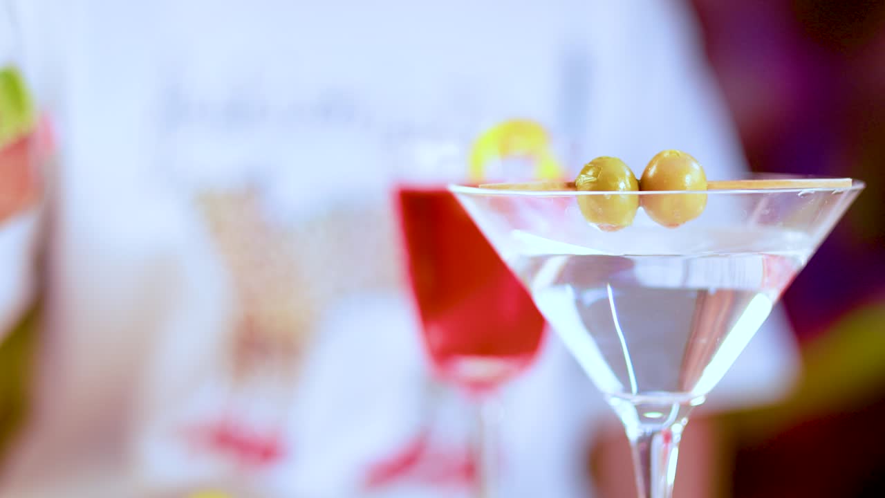 A vibrant display of cocktails including a martini with olives and a colorful drink with lime garnish in a lively setting