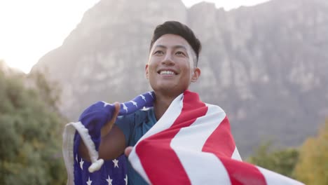 Retrato-De-Un-Hombre-Birracial-Sosteniendo-La-Bandera-De-Estados-Unidos-En-El-Jardín,-Cámara-Lenta