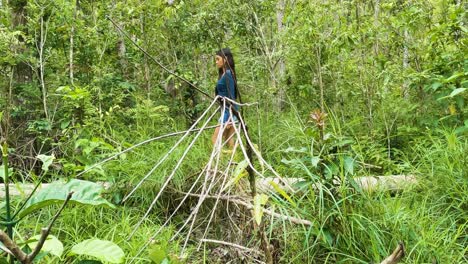 young woman in forest is walking behind dry plant branches