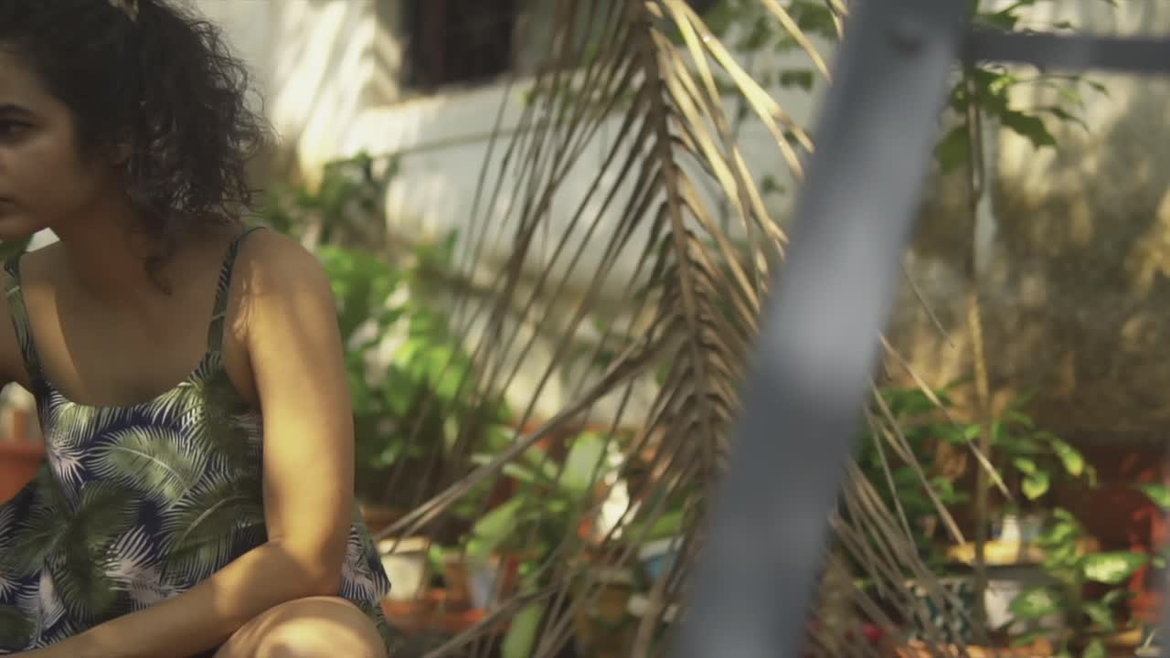 primer plano de una mujer joven con la mano sujetando la manguera de agua y regando las plantas en el jardín de verduras