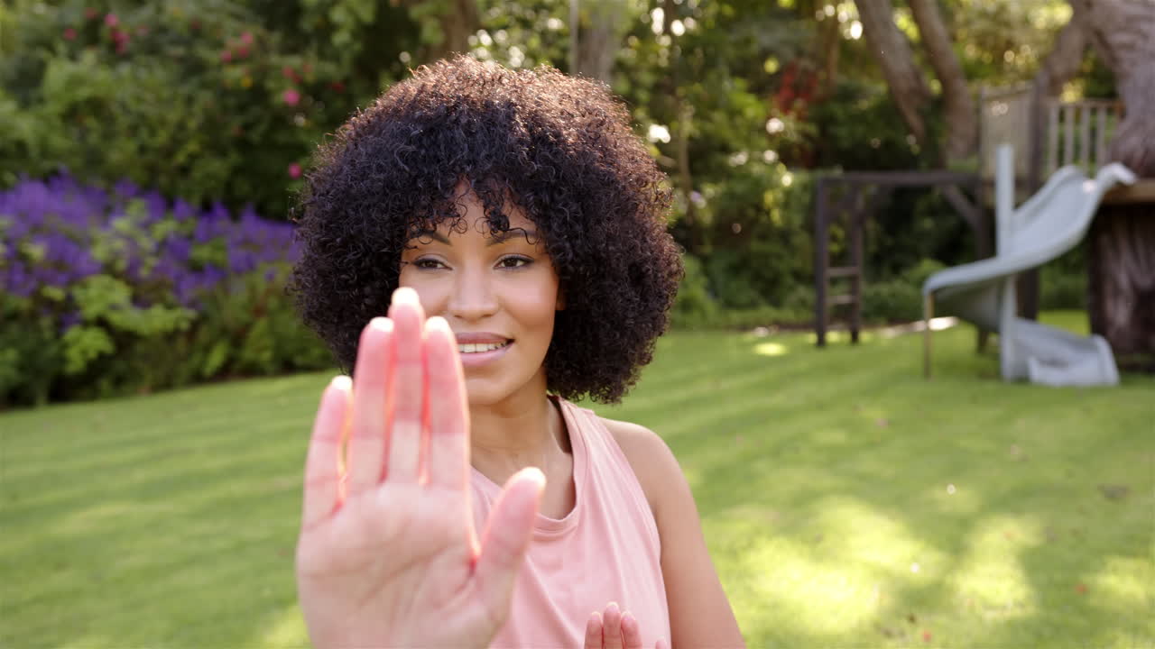 Practicing yoga, woman stretching arm forward in outdoor garden setting