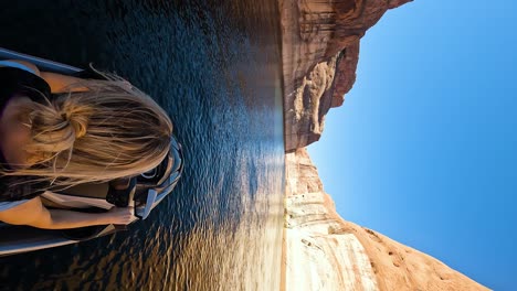 tomada vertical de una mujer conduciendo una moto acuática en el lago powell en el día del cielo azul, utah