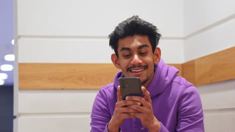 Sri-Lankan-man-listens-to-his-friend,-talks-and-looks-into-smartphone,-portrait-view