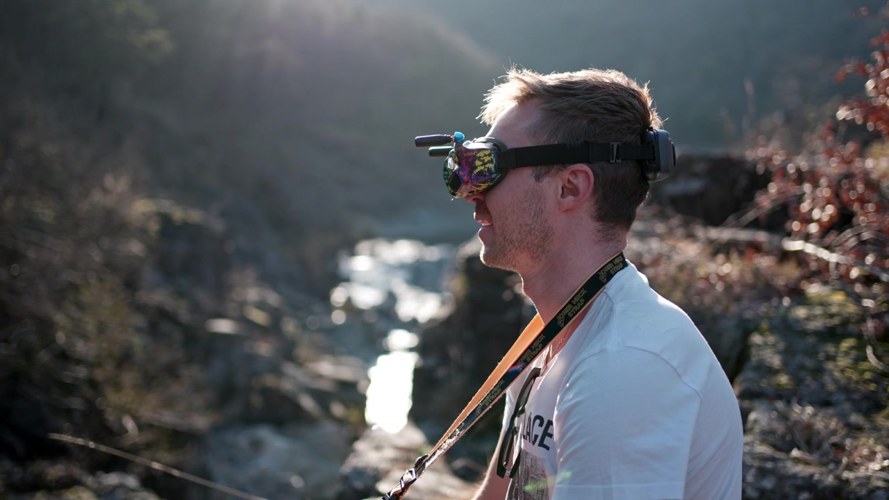 Drone pilot in nature with headset, filming outdoors with focused expression