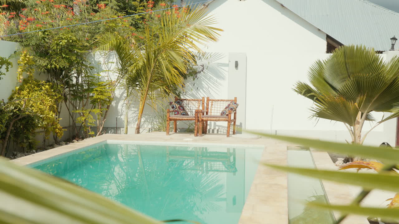 Steady shot capturing two inviting chairs set against the backdrop of a shimmering turquoise-blue pool located in a spa