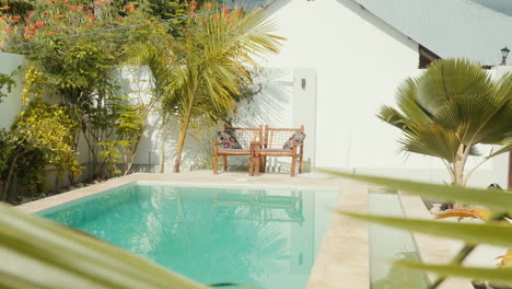 Steady-shot-capturing-two-inviting-chairs-set-against-the-backdrop-of-a-shimmering-turquoise-blue-pool-located-in-a-spa