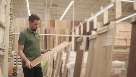 man selecting wood flooring in a home improvement store