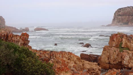 misty high key indian ocean waves crash into rich golden rocky shore