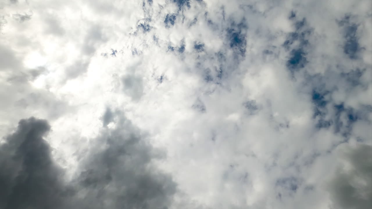Heavy white and gray clouds covering the sky. Low angle perspective timelapse of moving clouds.