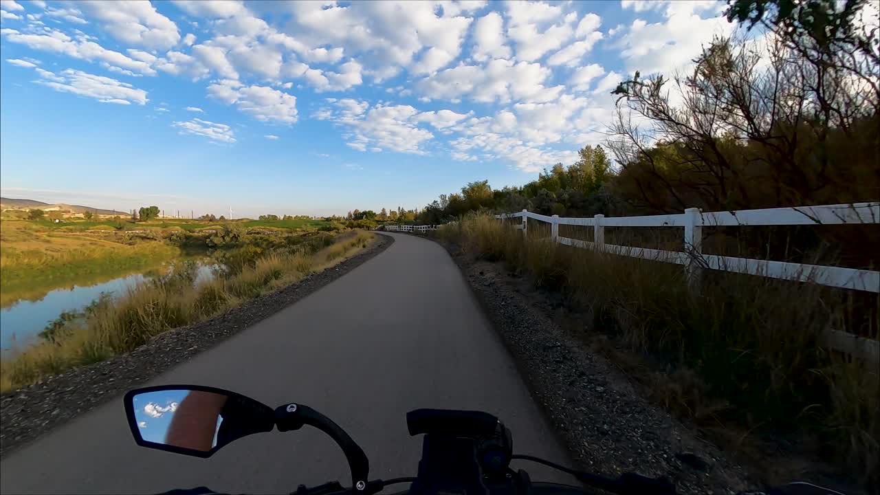 andar en bicicleta por un camino pavimentado junto a un río con el cielo reflejándose en el agua