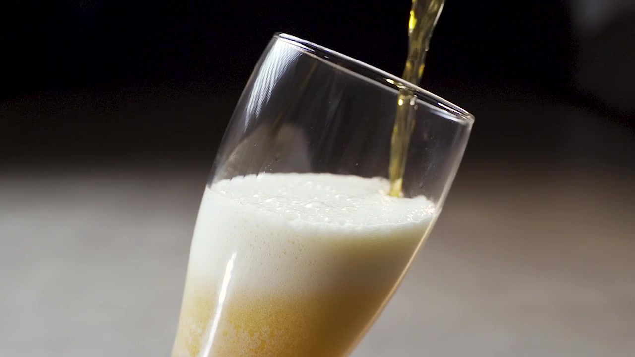 Slow motion pour of a light IPA style beer with a large amount of frothy foam.