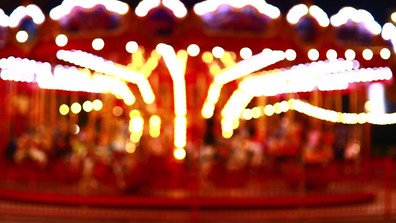 blurred unfocused video of brightly lit ferris wheel ride spinning at night