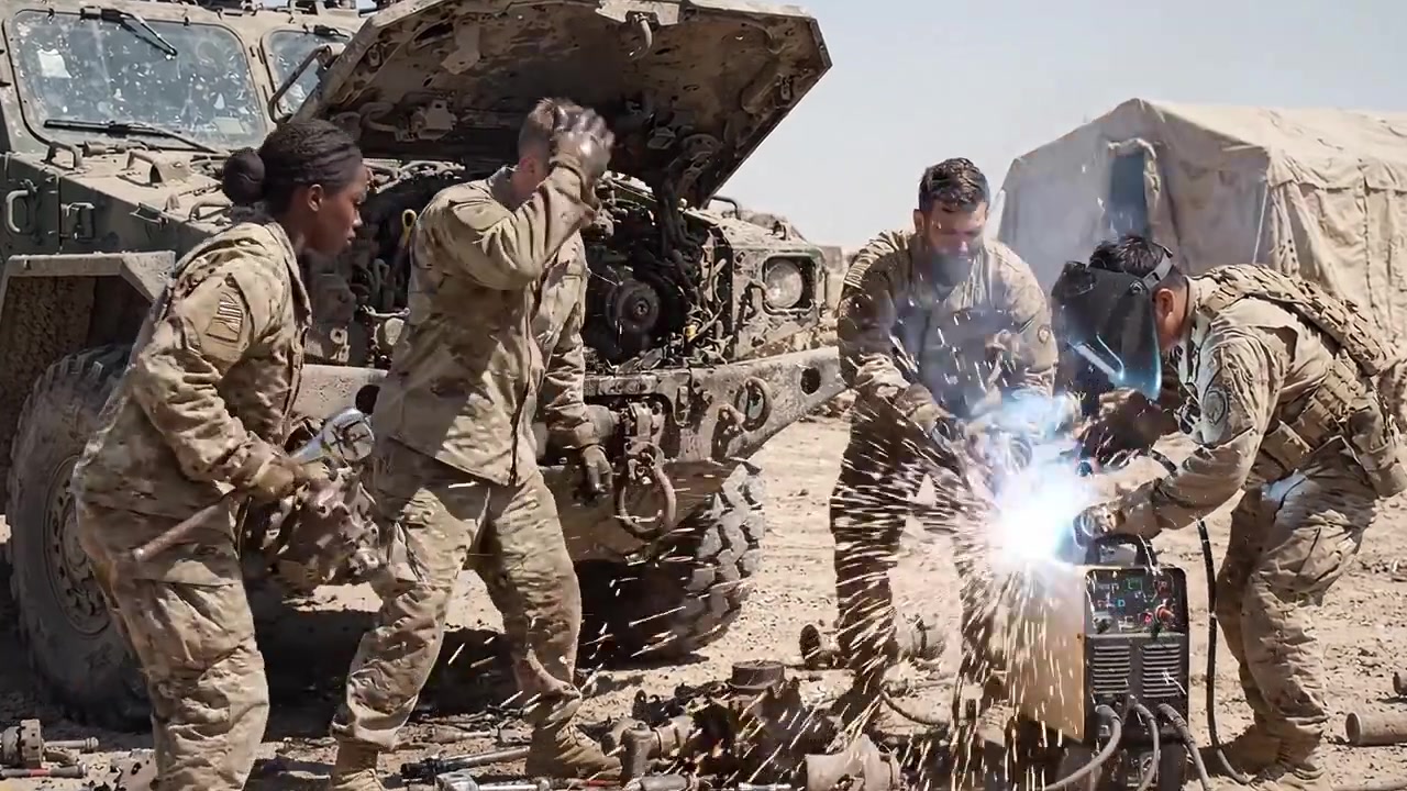 Personale militare che ripara un veicolo in un ambiente desertico con attrezzature per la saldatura e strumenti meccanici per un funzionamento e una manutenzione efficienti in condizioni difficili.
