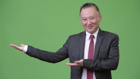 mature japanese businessman showing something