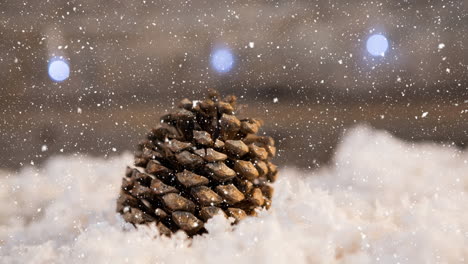 snow falling over pine cone on snow on wooden surface