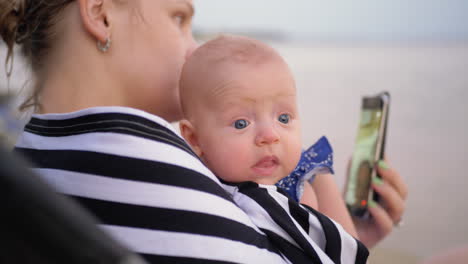 Madre-Con-Bebé-Video-Chateando-Por-Teléfono-Celular-En-La-Playa