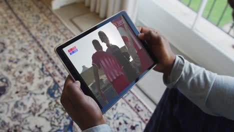 Composite-of-man-sitting-at-home,-watching-sports-event-on-tablet