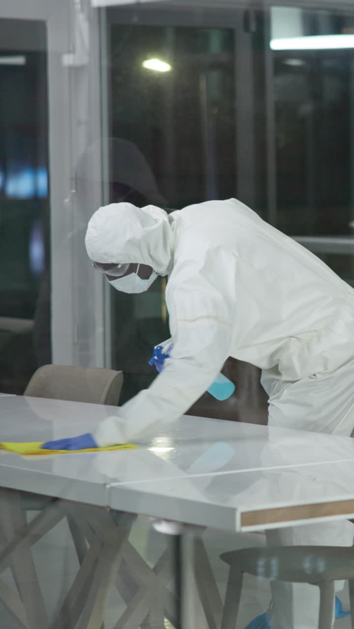 Person in hazmat suit disinfecting table