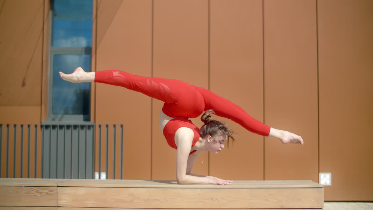 Woman performing acrobatic yoga poses outdoors