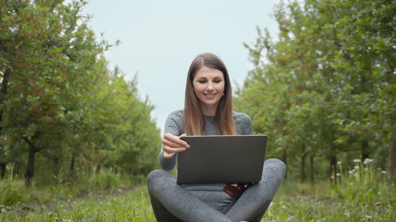 mujer trabajando en una computadora portátil en un huerto de manzanas