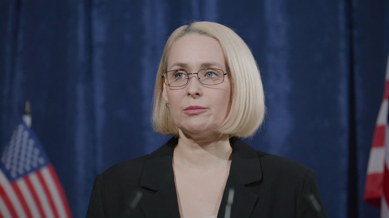 Mature Female Politician Speaking in front of Audience during Press Conference