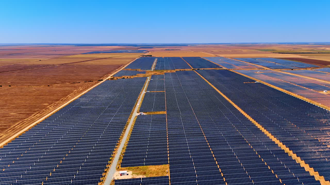 Flight over the enormous site of solar panels set in the countryside. Dry fields surround the area