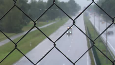 city traffic through fence in the raining day