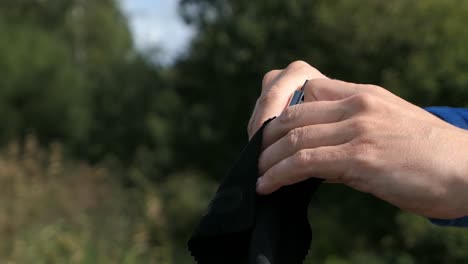 Person-wiping-harmonica-harp-in-nature-close-up