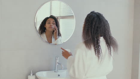 mujer aplicando crema para la cara en el baño