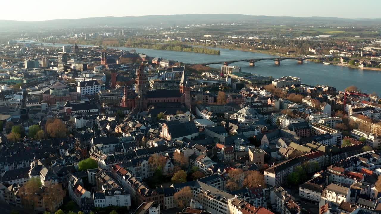 right to left drone move showing the Cathedral of Mainz in the middle of tiny houses on a warm spring day with the Rhine river in the back