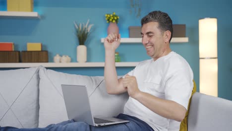 hombre de negocios trabajando en una computadora portátil en casa bailando con placer.