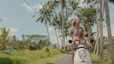 travel couple riding scooter on tropical island happy woman celebrating with arms raised enjoying fun vacation road trip with boyfriend on motorcycle ride