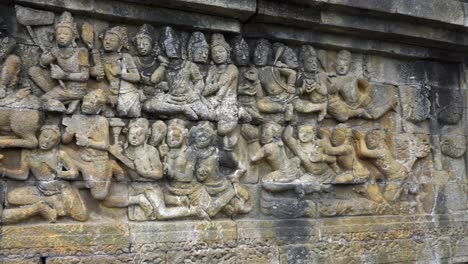 indonesia,jawa island,yogyakarta,unesco world heritage borobudur temple's inside,wall relief close up.camera slides slowly from right to left and shows the relief in details,army of people on the wall