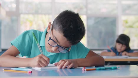 niño de escuela latino enfocado con gafas y haciendo la tarea