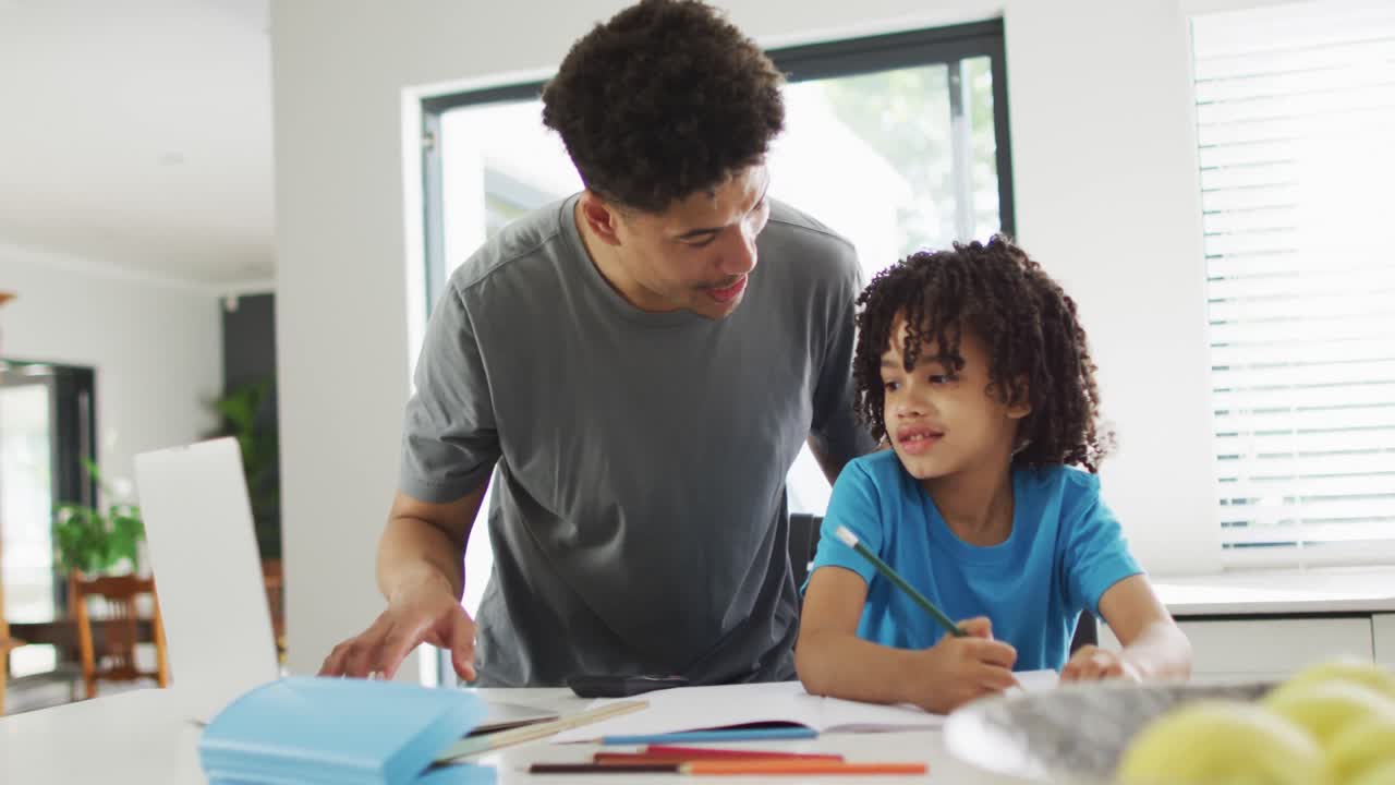 hombre biracial feliz y su hijo haciendo la tarea juntos