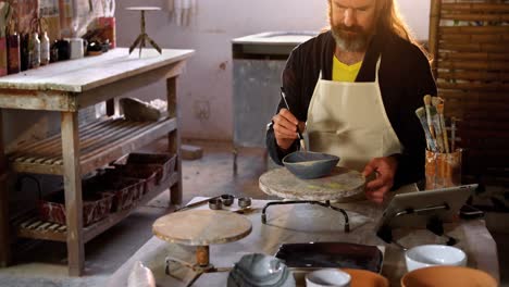 attentive male potter painting on bowl