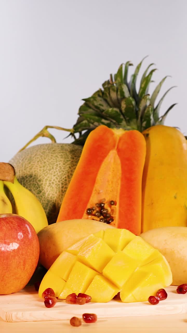 Una vivace disposizione verticale di frutta tropicale fresca, inclusi papaya a fette, mango e ananas.