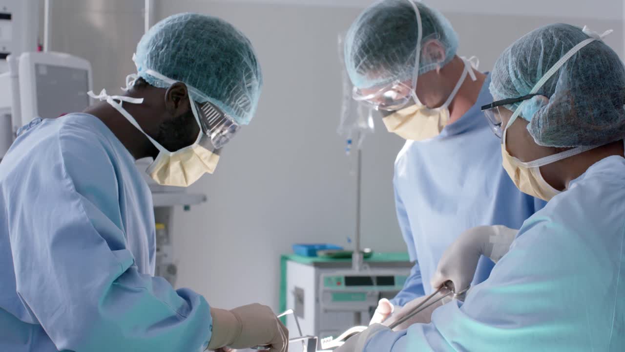 Focused diverse male and female surgeons with face masks during surgery in slow motion, unaltered