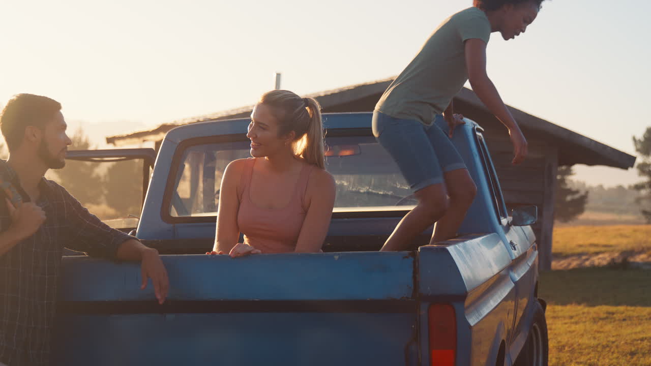 Freundesgruppe entlädt Rucksäcke von einem Pick-up-Truck auf dem Weg zu einer Landhütte