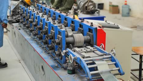 close-up sliding shot of a conveyor belt of a metal press from which a metal ribbon emerges