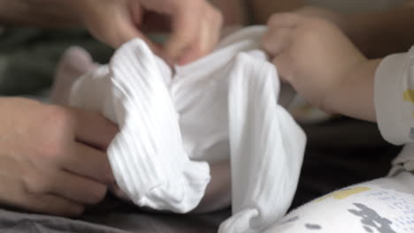 kid helping grandma to get baby into her clothes