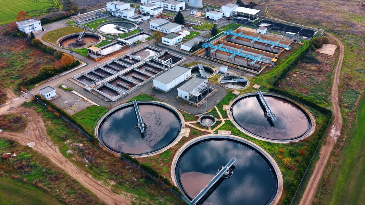 Flying away from the territory of modern wastewater treatment plant. Large circle basins are filled with sewage